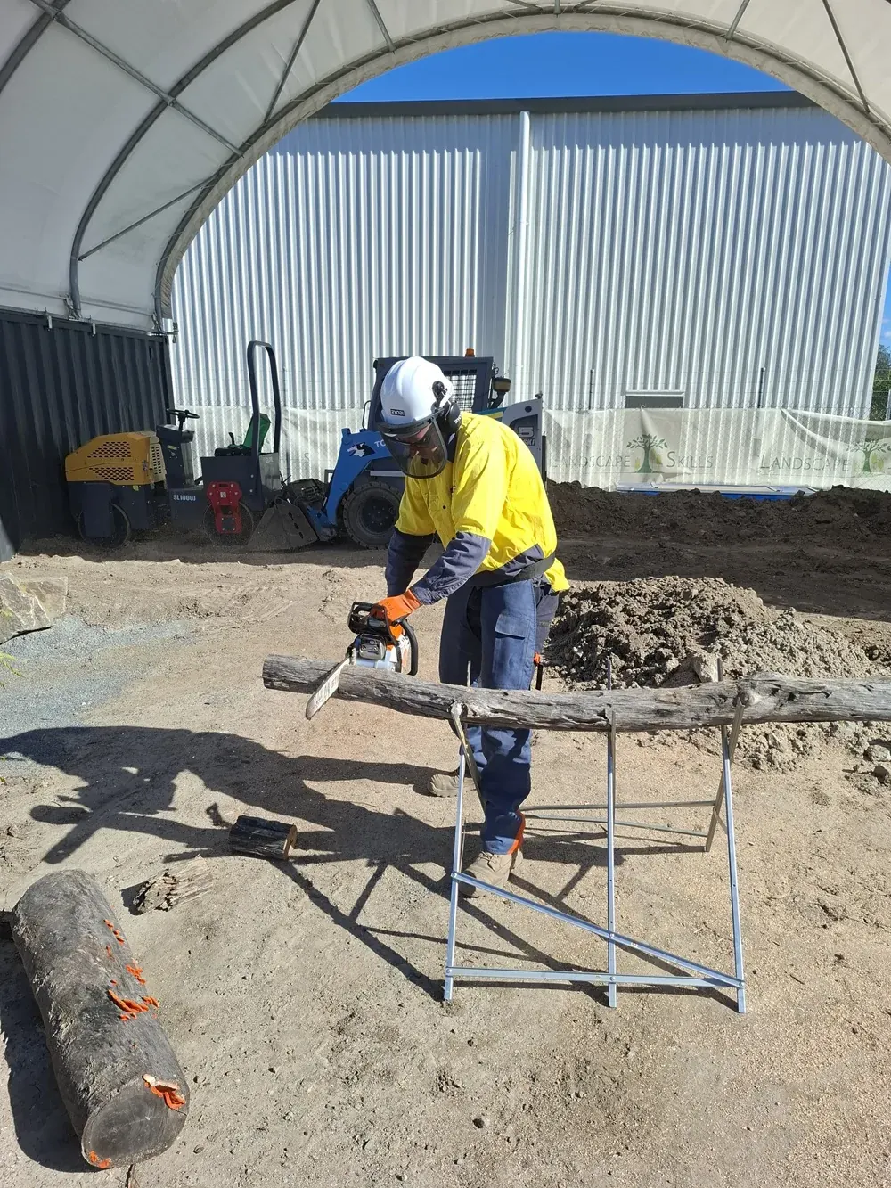 Trainee safely cross-cutting timber with a handheld chainsaw at Landscape Skills Logan Village training yard